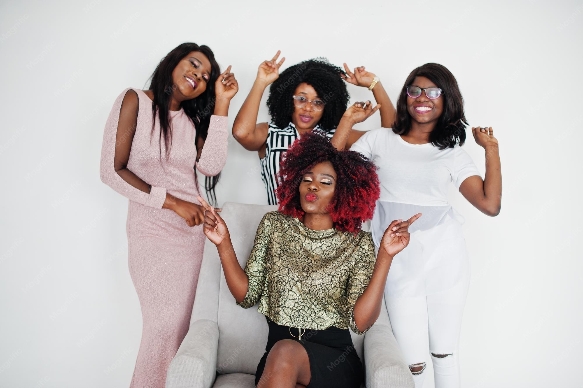 Four African girls celebrating together with hands raised, smiling on chairs